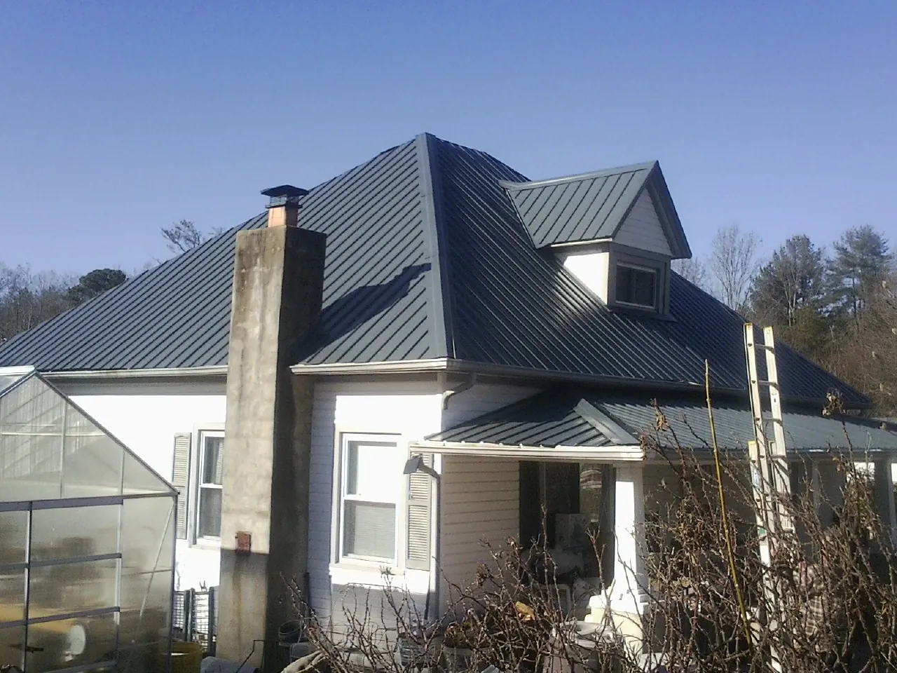 Dark blue standing seam metal roof on a white farmhouse with dormer — Slate & Tile Roof Repair by Roofing Brothers in Ludlow Falls