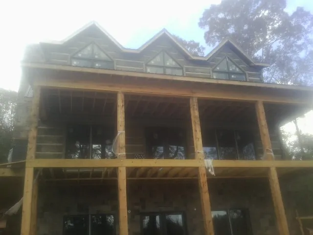Dormers and porch framing on a large log home under construction — Roof Coating work by our crew in Ludlow Falls