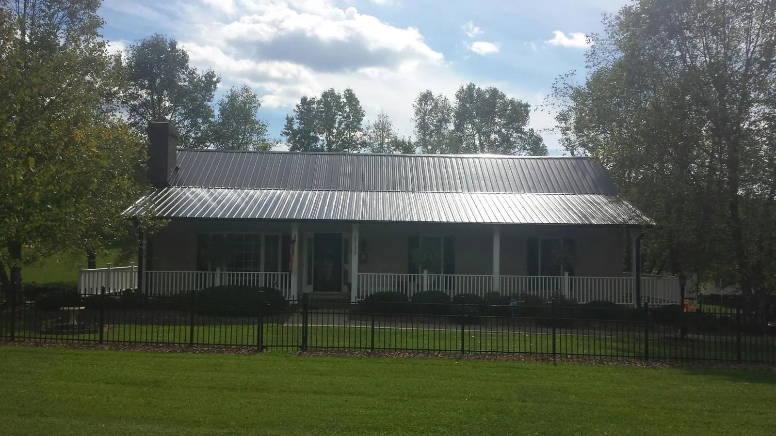 Gray metal roof on a brick ranch with a full width front porch — Gutter Guard Installation work by our crew in Ludlow Falls