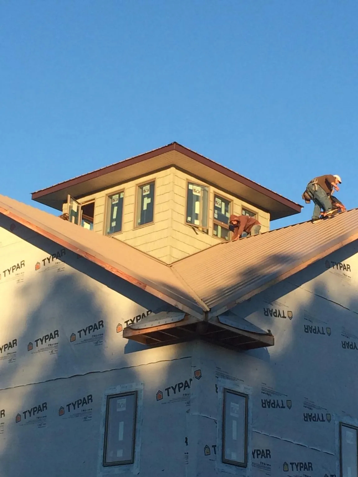 Roofers working around a rooftop cupola on a new metal roof at sunset — Roof Waterproofing in Ludlow Falls by Roofing Brothers